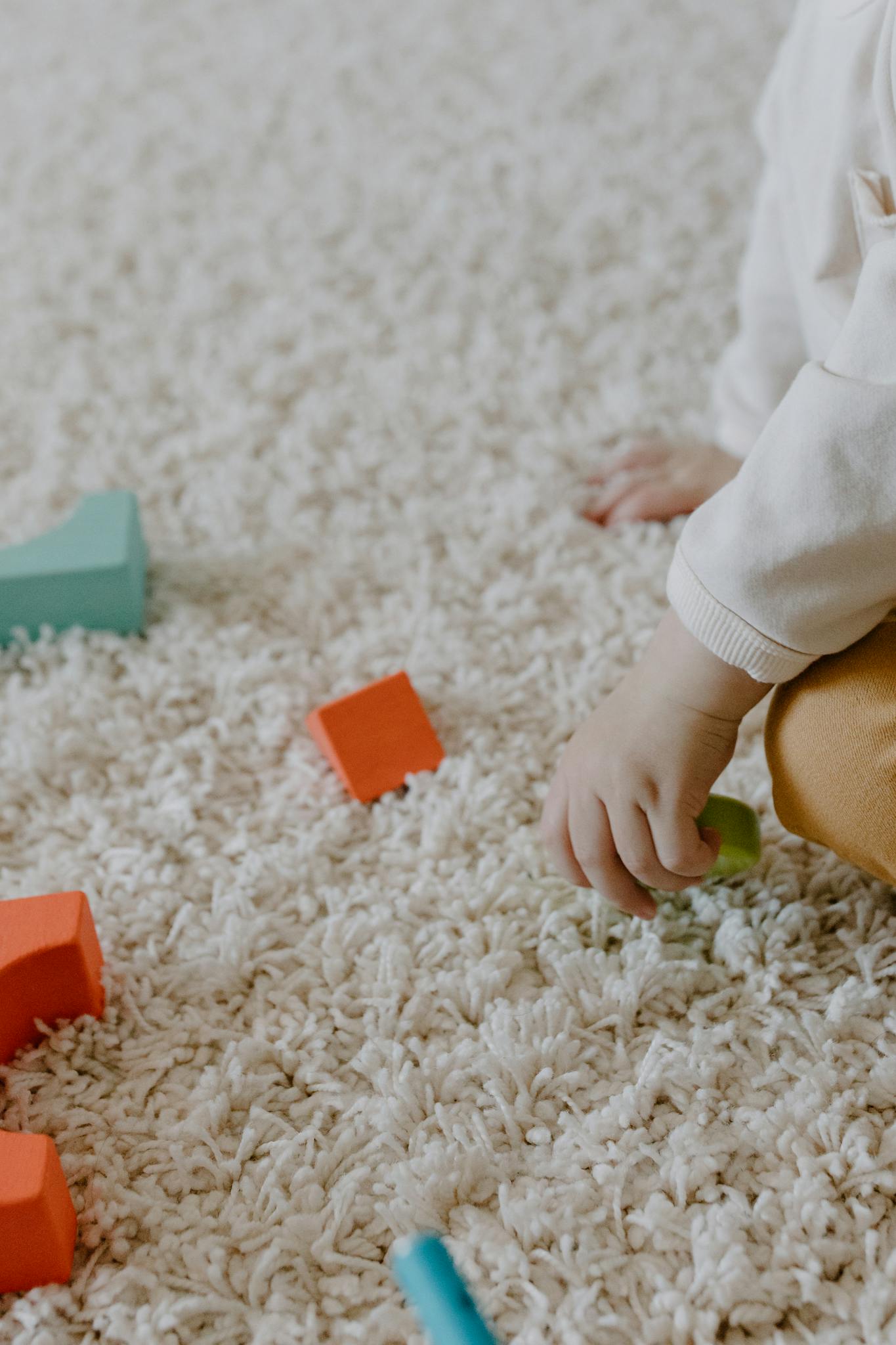 a childs hand arranging wooden blocks on